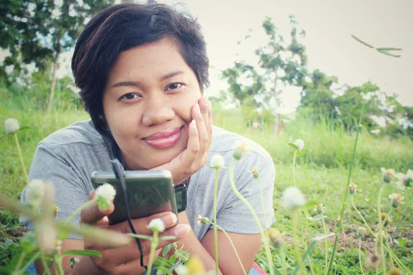 Vrouw luisteren naar muziek op oortelefoon met slimme telefoon in de tuin — Stockfoto