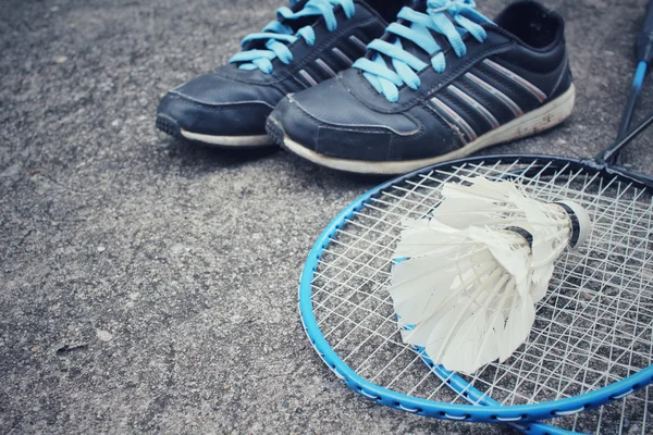 Sportschuhe mit Federhähnen und Badmintonschläger. — Stockfoto