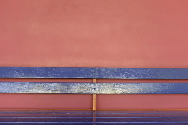 Niebieski drewna długiej ławce na tle różowe ściany — Zdjęcie stockowe
