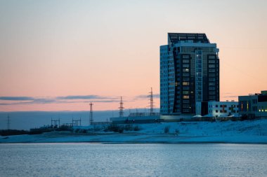 Yakutsk 'un yeni semtinde bir gökdelenin kış manzarası. Gün batımında Yakutsk City ufuk çizgisinde. Yeni bölgedeki bir gökdelende kış manzarası