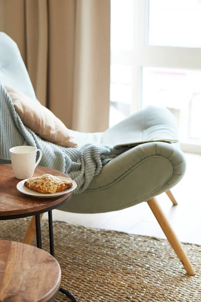 interior of a cozy room with a soft blue armchair and table with breakfast