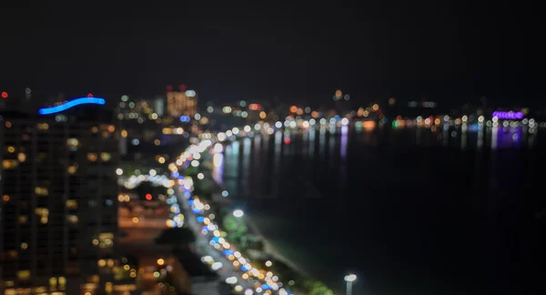 Luces borrosas de la ciudad con la playa iluminada por la noche —  Fotos de Stock