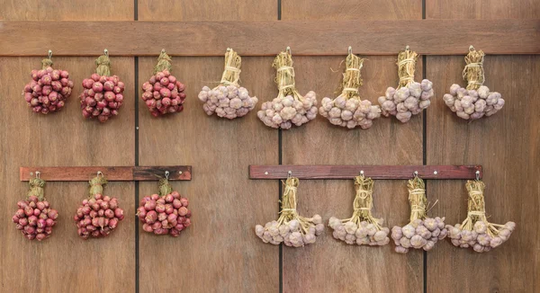 Rödlök och vitlök hängande på trävägg — Stockfoto