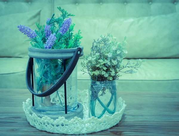 Flores artificiales sobre mesa de madera con fondo de sofá —  Fotos de Stock