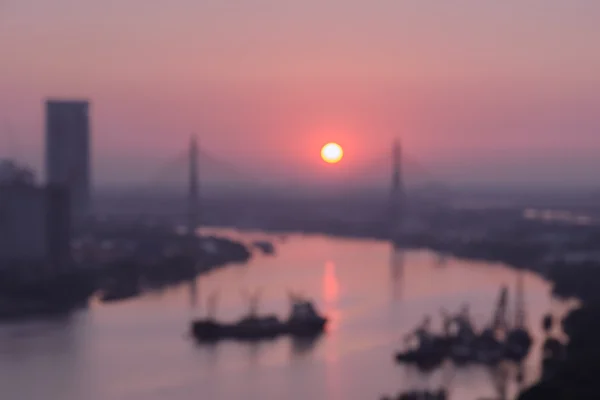 Nehir kenarında cityscape üzerinde gündoğumu ile soyut bulanık fotoğraf — Stok fotoğraf