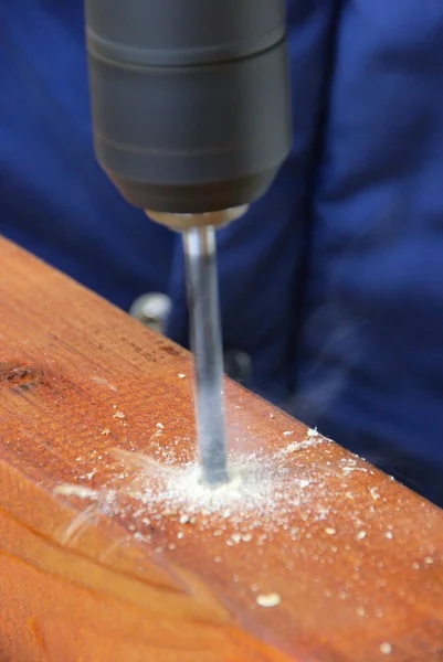 Drilling machine drills wooden plank — Stock Photo, Image