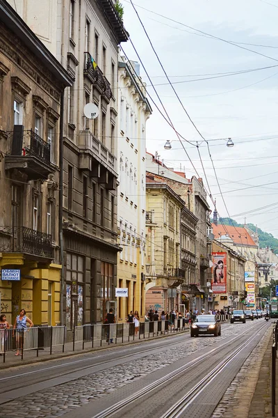 Lviv, Ucrania - 5 de agosto de 2015: Paisaje urbano de Lviv. Vista de la calle Lviv con la arquitectura antigua, coches y personas caminando . — Foto de Stock