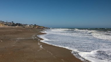 Califfornia, ABD 'de sahil boyunca dalgaların vurduğu sakin bir sahil sahnesi.