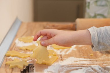 Çocuklar un ahşap tezgahta kurabiye hamuru, metal çam keskisi ve yakınlarda merdane.