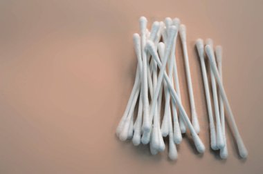 Sıcak bej bir yüzeye saçılmış beyaz pamuklu çubuklar. Tıp, güzellik ve temizlik temaları için temiz, basit ve çok yönlü resim.