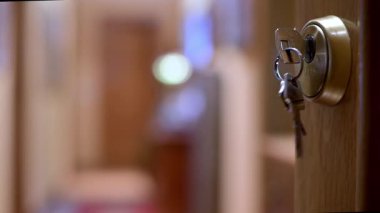 Sıcak bir koridorda, kapının kilidindeki anahtarlığın yakın çekim görüntüsü. Ev güvenliği, giriş, güvenlik ve günlük yaşam anlarını iletir..