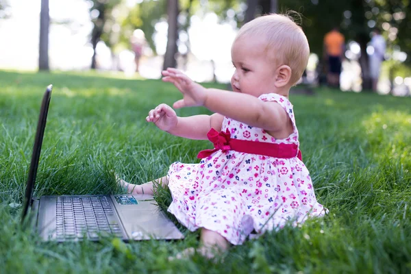 Niña sentada en la hierba y jugando tableta pc, tonificación de la foto — Foto de Stock