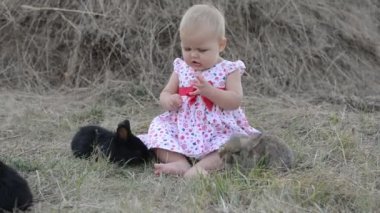 Sevimli güzel gülen genç kız beyaz ve siyah bebeği tavşan çim üzerinde
