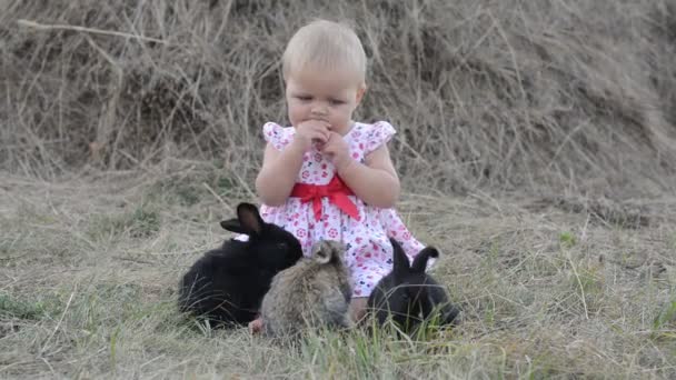 Niedlich schöne lachende Teenie-Mädchen auf Gras mit weißen und schwarzen Baby-Kaninchen — Stockvideo