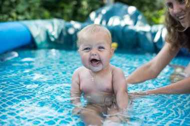 Bir Yüzme Havuzu kenarında rahatlatıcı sevimli mutlu genç kadın kız çocuk bebek