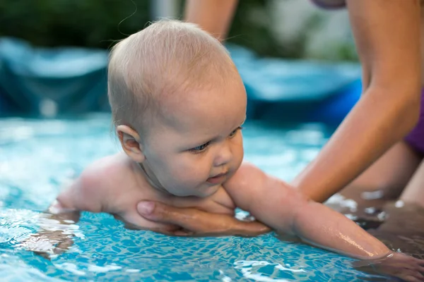 Un lindo bebé de niña joven y feliz que se relaja al lado de una piscina — Foto de Stock