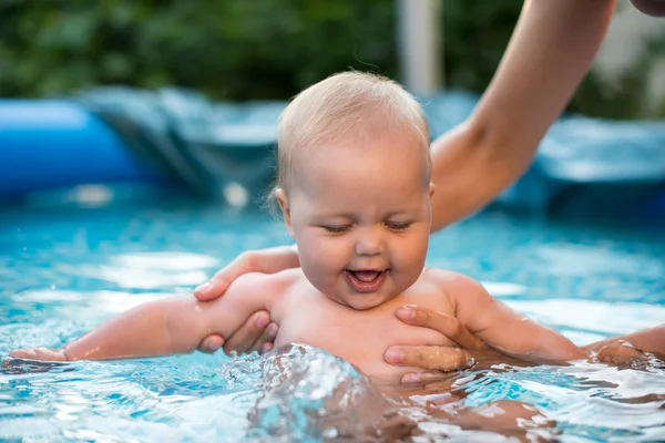 Un lindo bebé de niña joven y feliz que se relaja al lado de una piscina — Foto de Stock