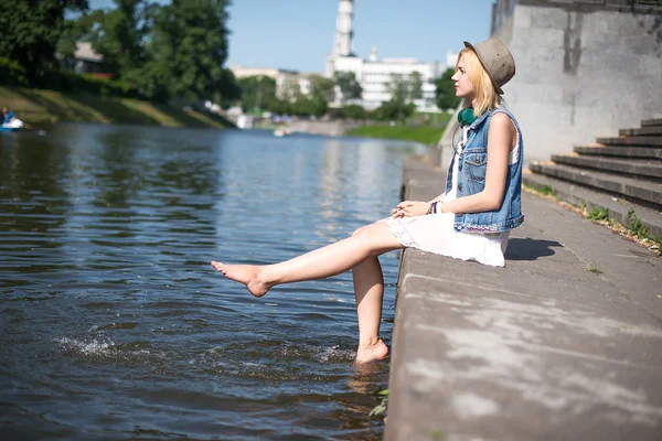 Meisje zitten op de pier en opknoping blote voeten — Stockfoto