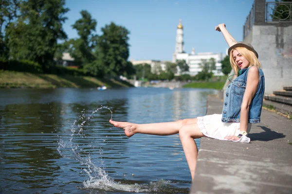 Dívka sedí u mola a visí bosé nohy — Stock fotografie