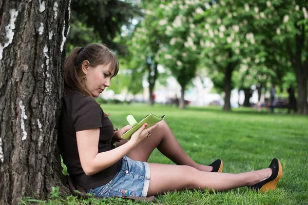 Jeune femme lisant un livre dans le parc municipal — Photo