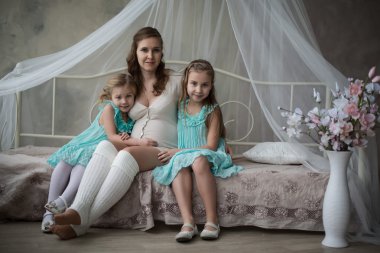 Genç bir hamile anne ve genç yürümeye başlayan çocuk kızı yatakta oynak ve having fun evde iken üzerinde kafa görünümünü