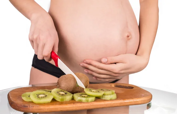 Portret van zwangere moeder snijdt kiwi vruchten — Stockfoto