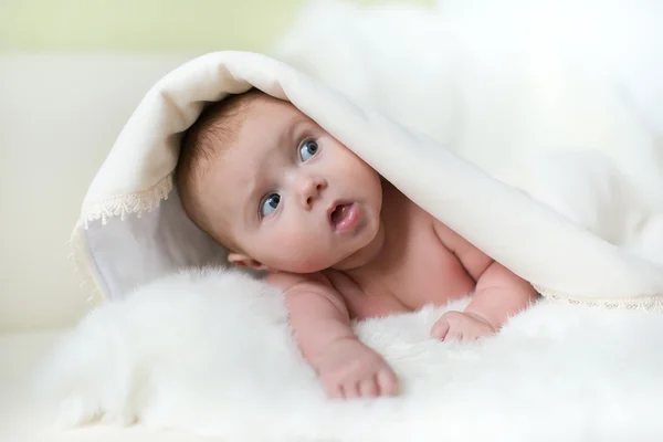O bebê surpreso deitado na toalha branca — Fotografia de Stock