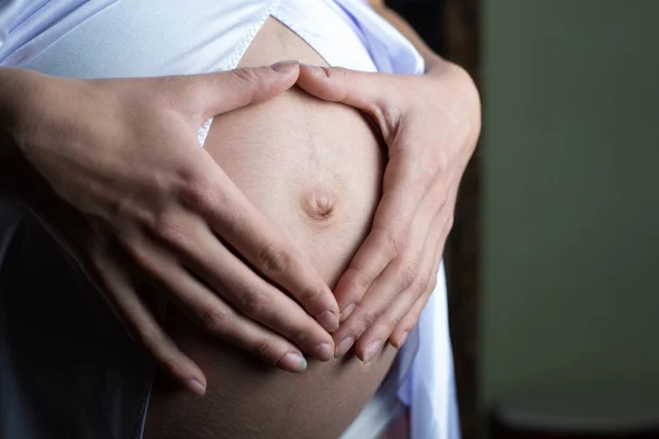 Mulher grávida conceito de gravidez coração no estômago. Mãos a formar coração no umbigo feminino. Conceito de saúde do estômago saudável, ou conceito de gravidez precoce com belas mãos femininas. Modelo de mulher . — Fotografia de Stock