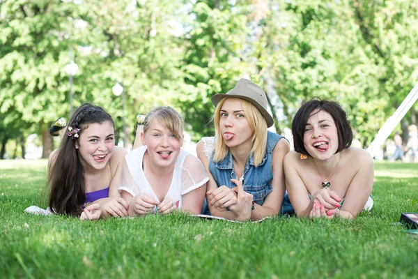 Grupo de felices estudiantes adolescentes sonrientes afuera tumbados en una hierba — Foto de Stock