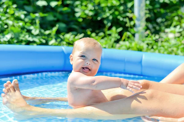 Un niño pequeño y feliz está jugando afuera en una piscina de bebé o Imagen De Stock