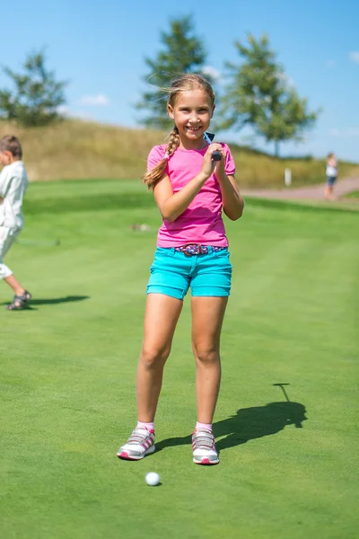 Menina bonito jogar golfe em um campo ao ar livre. Hora de Verão — Fotografia de Stock