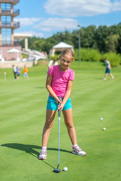 Linda niña jugando al golf en un campo al aire libre. Verano. Imágenes de stock libres de derechos