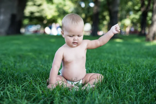 Bebé feliz con el pelo ligero y esponjoso sentado en la hierba y riendo. Verano y muy cálido. Feliz. — Foto de Stock