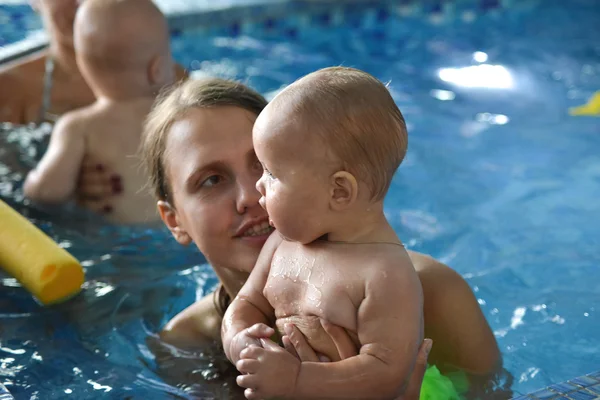 Familia joven con bebé divirtiéndose en la piscina . — Foto de Stock