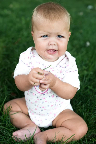 Bébé heureux avec des cheveux légers et duveteux assis sur l'herbe — Photo