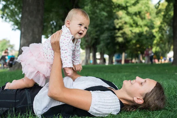 Moeder en kind spelen in het park op het gras — Stockfoto