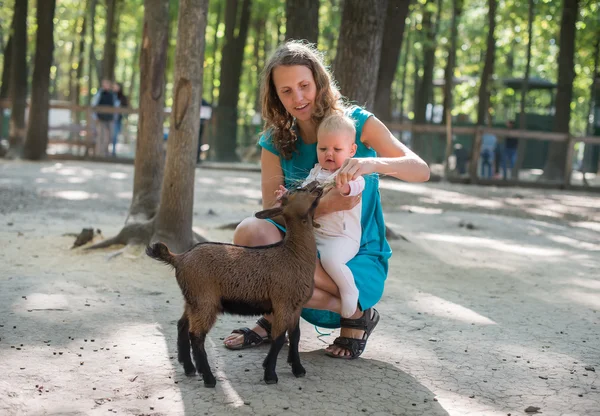 Happy mother and her daughter with baby goats on the countryside — Stock Photo, Image