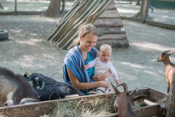 Happy mother and her daughter with baby goats on the countryside — Stock Photo, Image