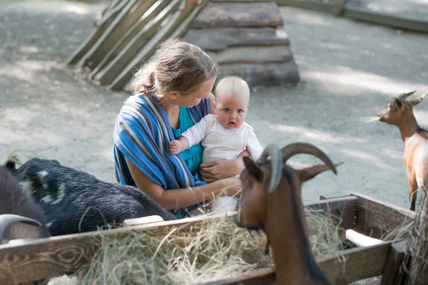 Happy mother and her daughter with baby goats on the countryside — Stock Photo, Image