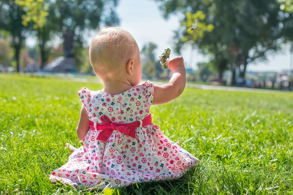 Playful girl sitting on a meadow. Cute baby. — Stock Photo, Image