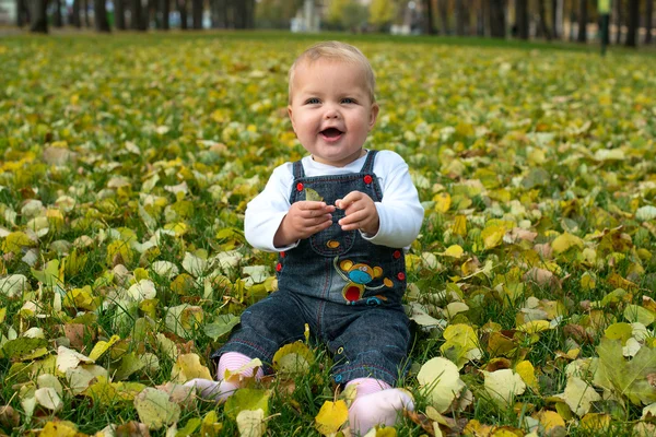 Beautiful little girl standing in a park in autumn — Stock Photo, Image