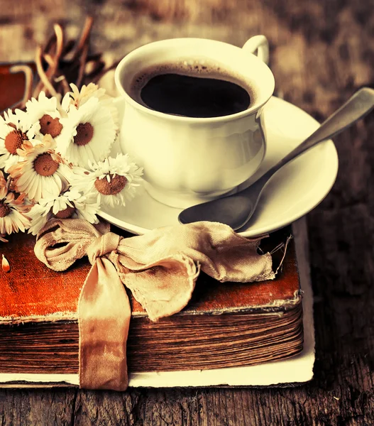 Uma xícara de café quente, flores e livro . — Fotografia de Stock