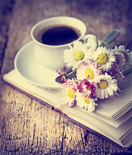 En kopp hett kaffe, blommor och bok. — Stockfoto