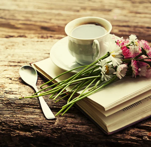 En kopp hett kaffe, blommor och bok. — Stockfoto