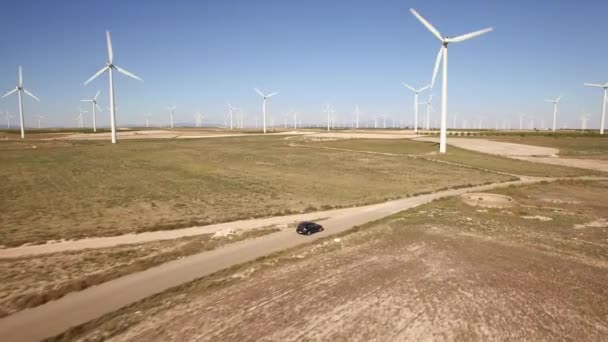 Following a black car in windmill farm — Stock Video