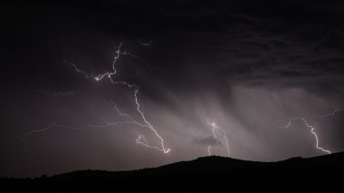 Lightning strike over mountain range with clouds clipart