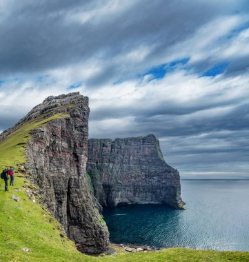 Faroe Adaları 'ndaki yüksek kayalıkların fotoğraflarını çeken turistler
