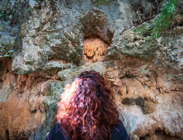 Mujer jengibre irreconocible observa las estalactitas sobre las rocas —  Fotos de Stock