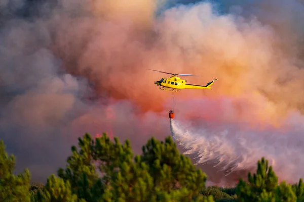Smoke and helicopter dumping water with bambi-bucket