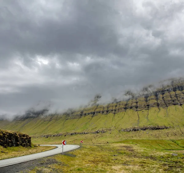 Böjd väg till bergen under molnig himmel — Stockfoto